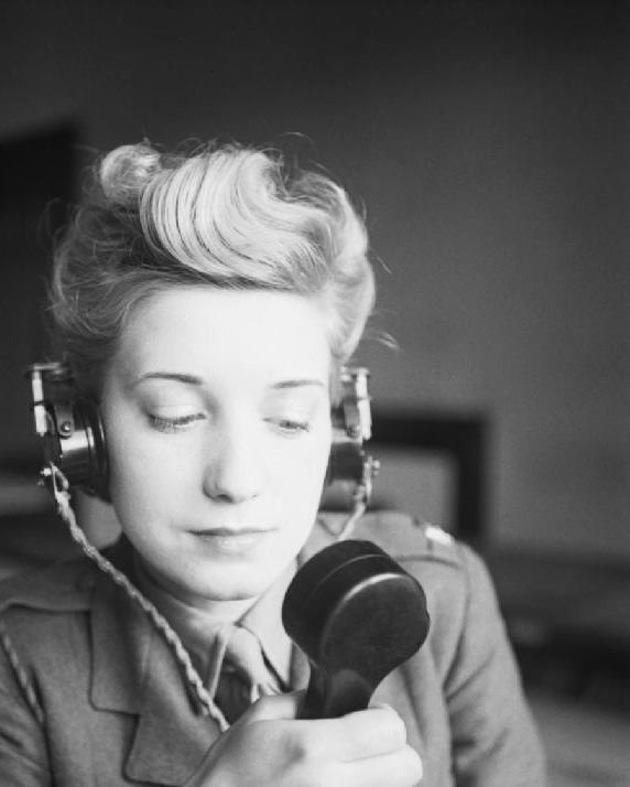 Black and white image of a woman in uniform wearing a headset.